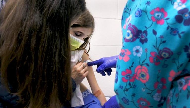 طفلة تتلقى تطعيما ووالدتها بجوارها