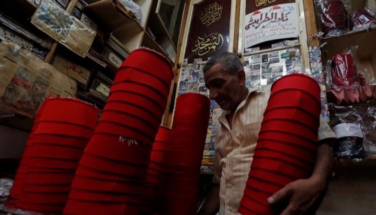 عبدالباسط يحمل مجموعة من الطرابيش التي صنعها بنفسه في مصر