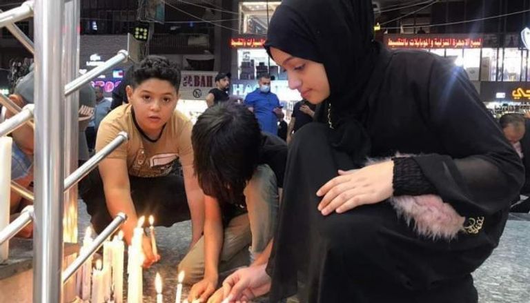 أهالي ضحايا يشعلون الشموع في موقع تفجير الكرادة
