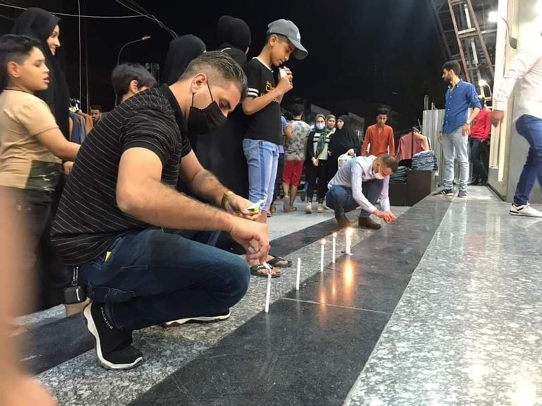 أهالي ضحايا يشعلون الشموع في موقع تفجير الكرادة