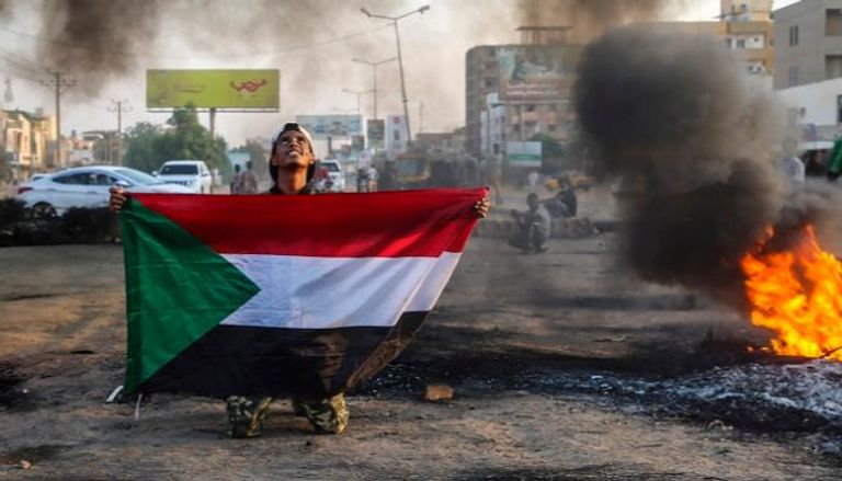 متظاهر يرفع علم السودان خلال احتجاجات