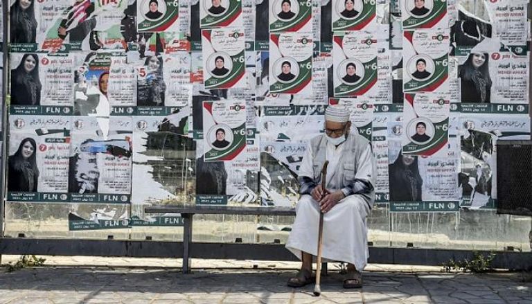 جزائري يتوسط ملصقات انتخابية في العاصمة - أرشيفية