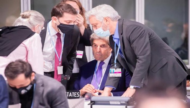 جون كيري مبعوث الرئيس الأمريكي للمناخ محاطًا بالموظفين خلال COP26 