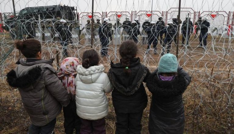 أطفال مهاجرون على السياج الحدودي بين بيلاروسيا وبولندا