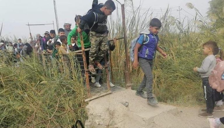تلاميذ يحاولون عبور ممر ضيق شرق العراق