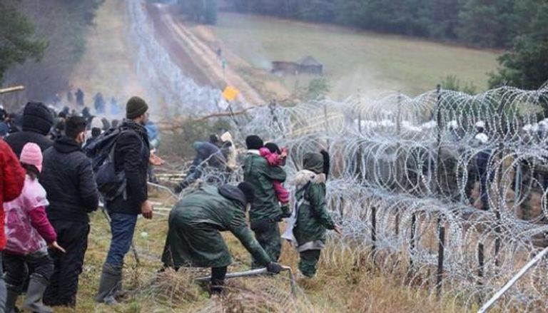 مهاجرون أمام الأسلاك الشائكة على حدود بولندا- أ.ف.ب 