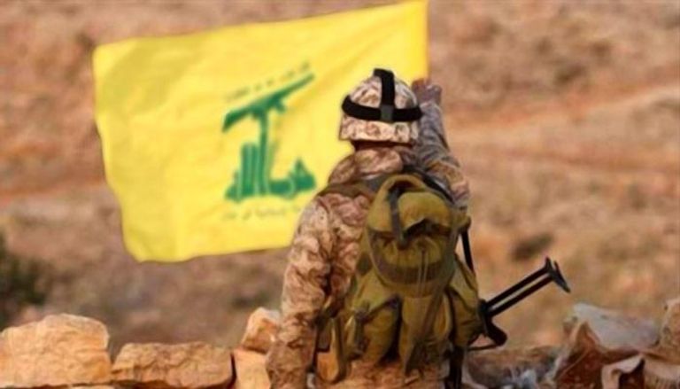 أحد عناصر حزب الله يقف أمام رايه الحزب في لبنان- أرشيفية