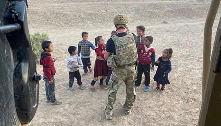 أحد جنود العمليات الخاصة الأمريكية يوزع المساعدات في قرية سورية