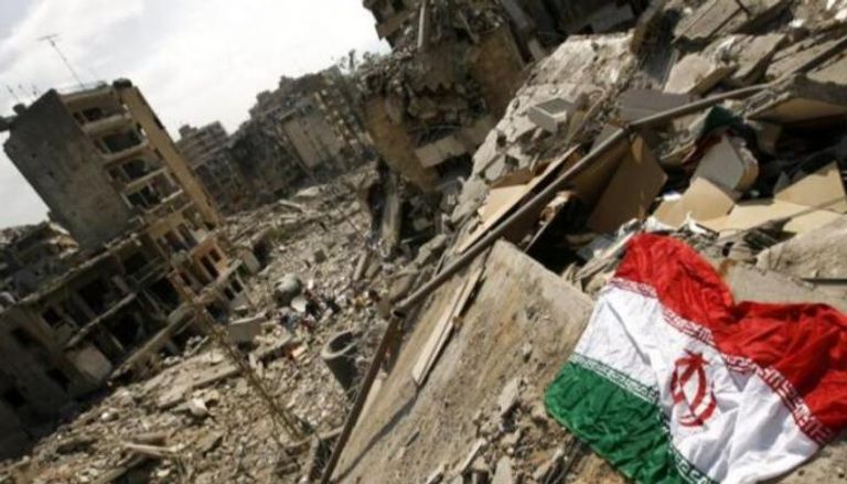 علم إيران فوق ركام أحد المباني المدمرة في سوريا
