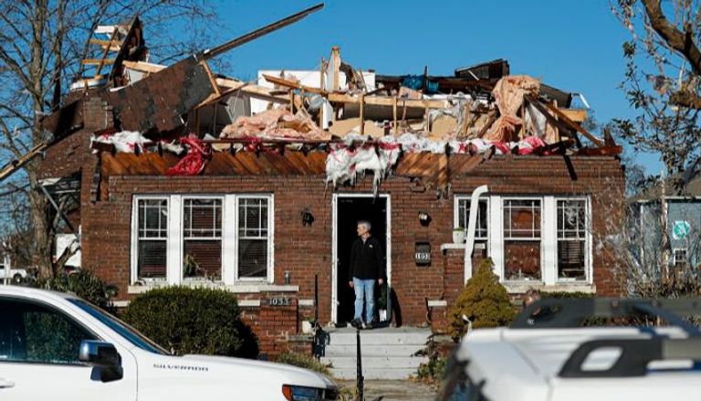 رجل يقف أمام منزله الذي دمرته الأعاصير في ولاية كنتاكي