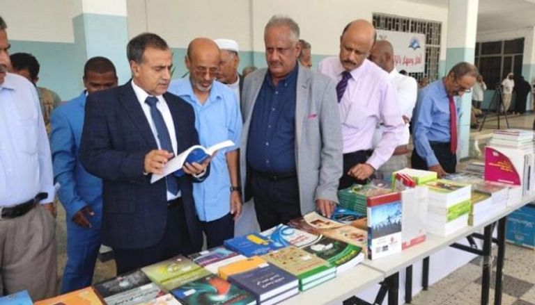 رئيس جامعة عدن يستعرض أحد الكتب داخل المعرض