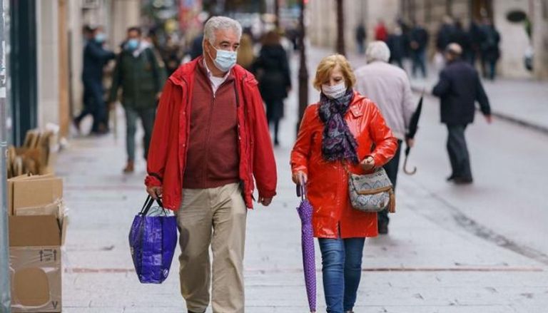 رجل وامرأة يرتديان كمامة للوقاية من فيروس كورونا في إسبانيا