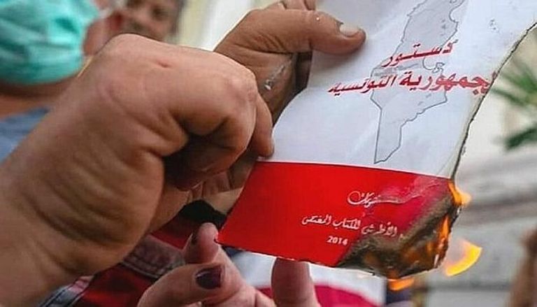 أحد المحتجين يحرق كتيبا للدستور 2014 الذي صاغه الإخوان في تونس