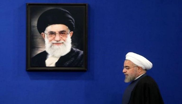 حسن روحاني وفي الخلفية صورة لمرشد إيران