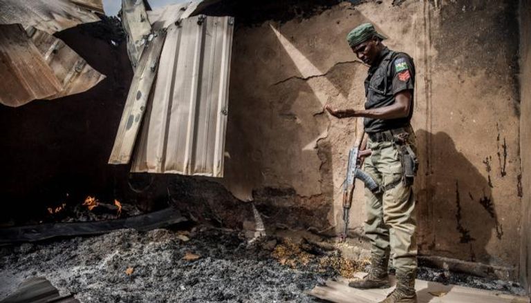 شرطي نيجيري يقف على أطلال منزل مدمر إثر هجوم استهدف إحدى القرى