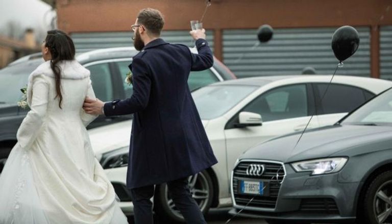 العروسان أثناء تحيتهما للضيوف الجالسين داخل سياراتهم