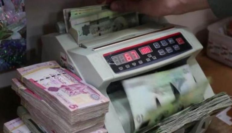 موظف بأحد مصارف ليبيا يحصي أوراقًا من فئة الـ10 دنانير (أرشيفية)