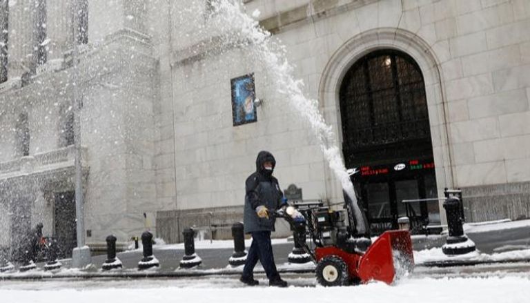 عامل يزيل الثلج من رصيف خارج بورصة نيويورك - رويترز