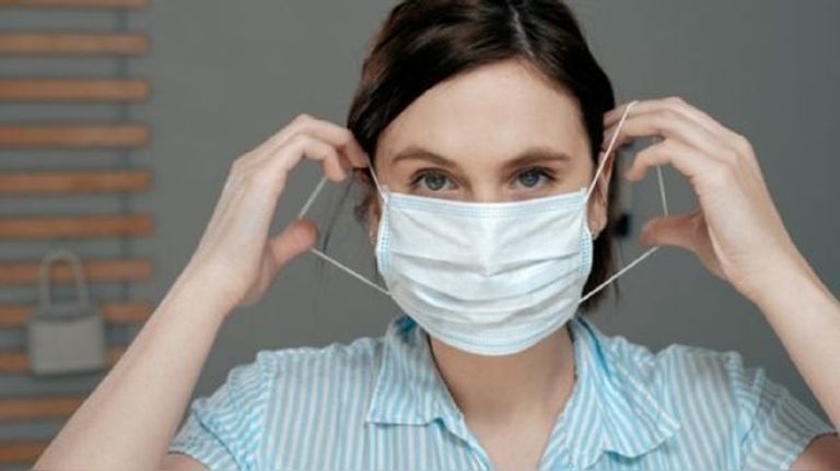 كورونا حول العالم امرأة تضبط الكمامة على وجه طفل