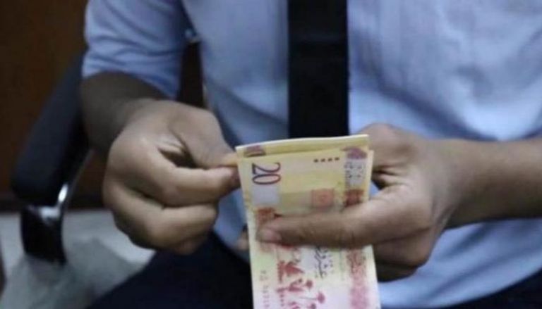 موظف بأحد مصارف ليبيا يحصي أوراقًا من فئة الـ20 دينارًا. (أرشيفية)