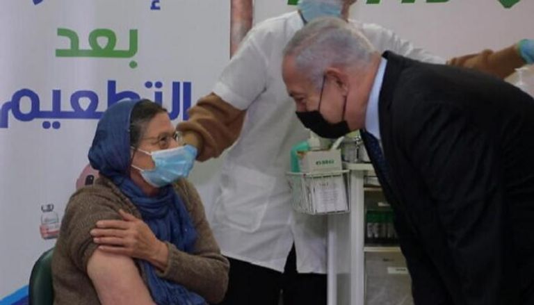 نتنياهو يتحدث مع سيدة تتلقى تطعيم كورونا