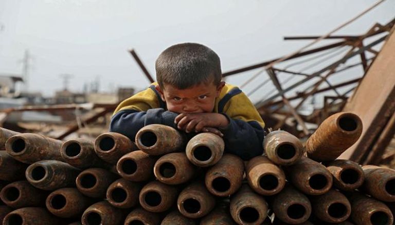 طفل سوري يجوار القذائف الفارغة