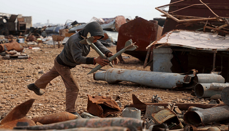 طفل سوري يجوار القذائف الفارغة