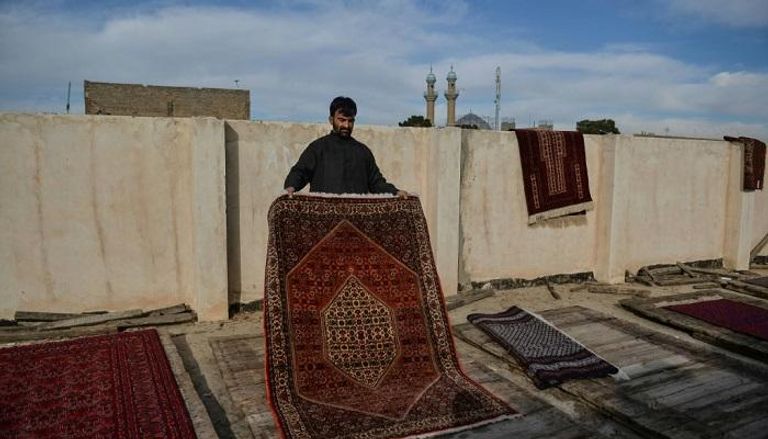 تاجر يعمل على تجفيف سجاداته بتعريضها لاشعة الشمس في مدينة هيرات الأفغانية