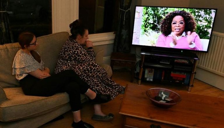 أوبرا وينفري على شاشة تلفزيون بمنزل عائلة تشاهد المقابلة مع هاري وميجان