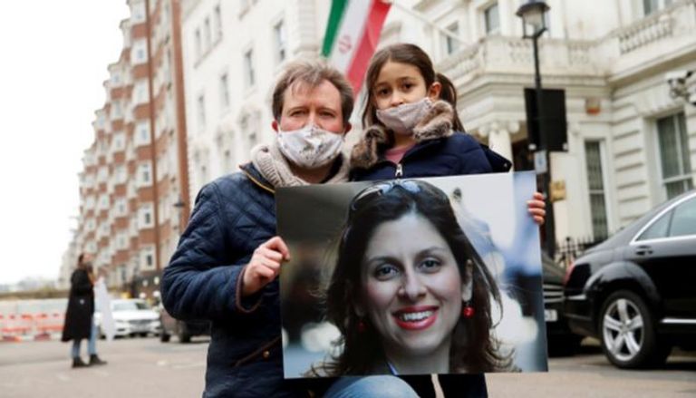 زوج نازانين زاغاري وابنتها خلال وقفة احتجاجية أمام سفارة طهران بلندن - رويترز