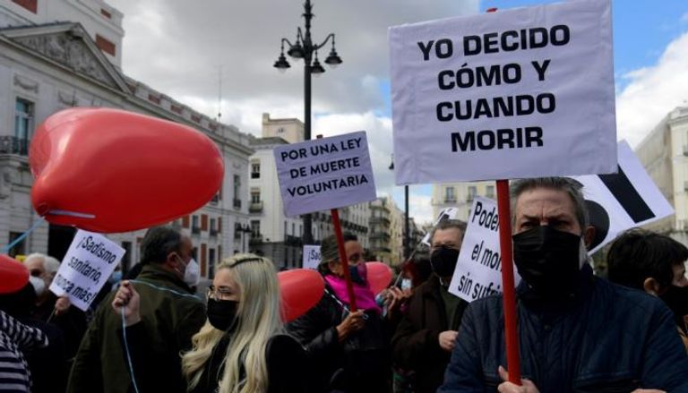 رجل يحمل لافتة كتب عليها "أنا أقرر متى وكيف أموت" خلال تظاهرة في مدريد