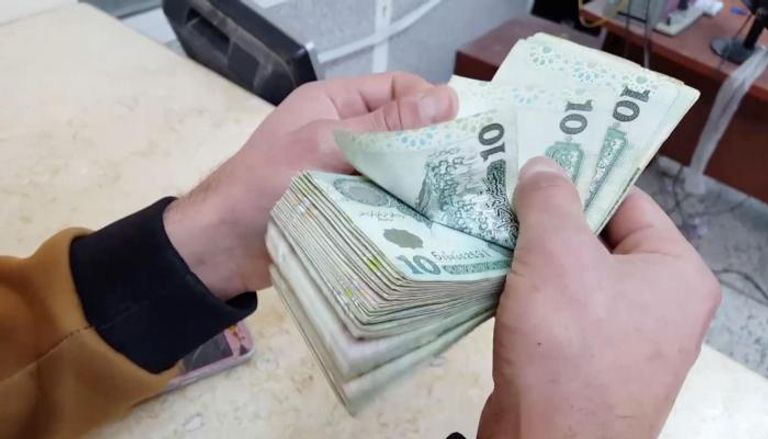 موظف بأحد مصارف ليبيا يحصي أوراقًا من فئة الـ10 دينارات. (أرشيفية)