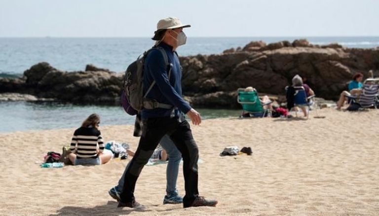 رجل يضع كمامة على شاطئ قرب منطقة جيرونا الإسبانية- أ ف ب