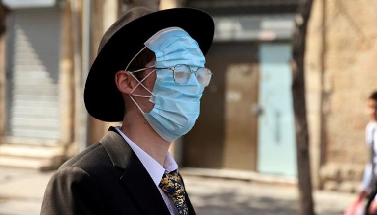 إسرائيلي يرتدي كمامتين بشكل غريب للوقاية من فيروس كورونا