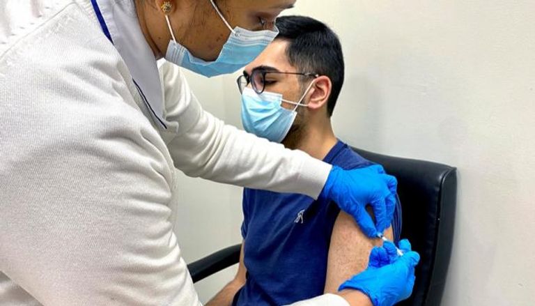 شاب يتلقى التطعيم ضد كورونا في دبي