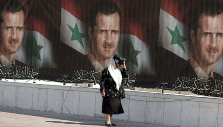 سيدة تسير بجوار لافتات انتخابية للأسد - أرشيفية