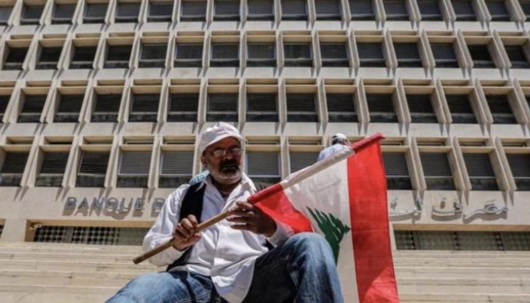 رجل يحمل علم لبنان أمام المصرف المركزي