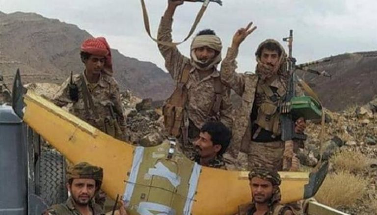 عناصر الجيش اليمني بجانب الطائرة الحوثية التي تم إسقاطها
