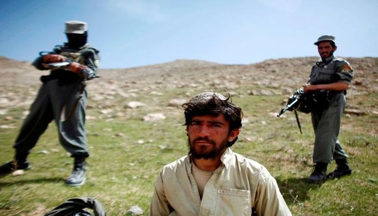 رجال شرطة أفغان يقفون خلف أحد أسرى حركة طالبان