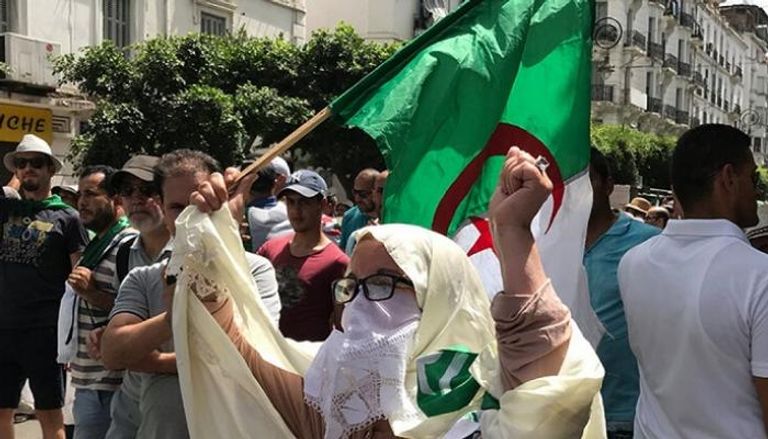 سيدة جزائرية ترفع علم بلادها في مظاهرة 