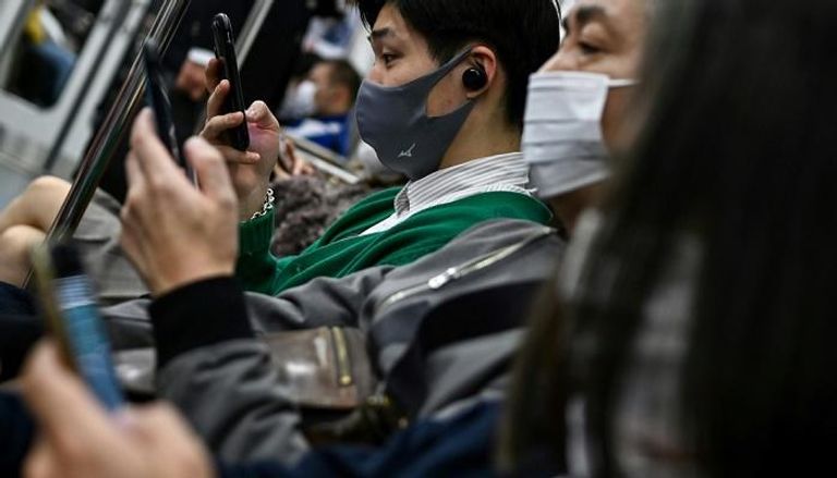 ركاب يستخدمون هواتفهم المحمولة في وسائل النقل العام في طوكيو