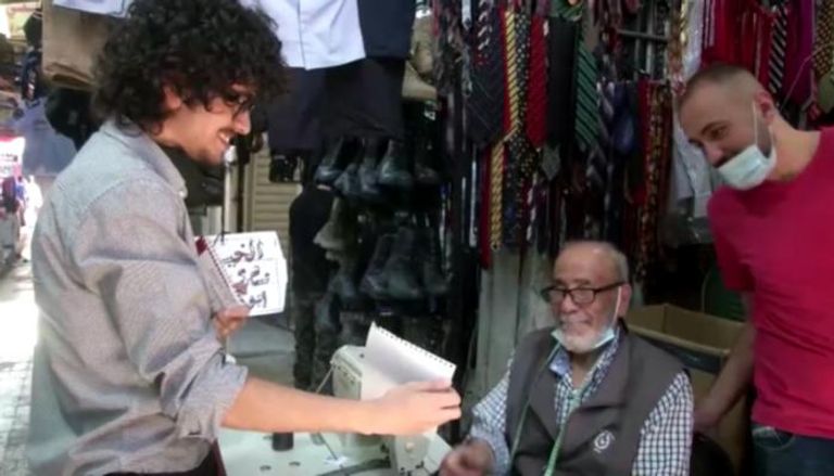 الشاب الأردني أحمد الريماوي يقدم رسمة لأحد الأشخاص