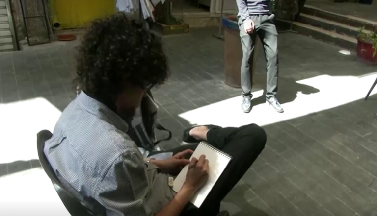 الشاب الأردني أحمد الريماوي يقدم رسمة لأحد الأشخاص