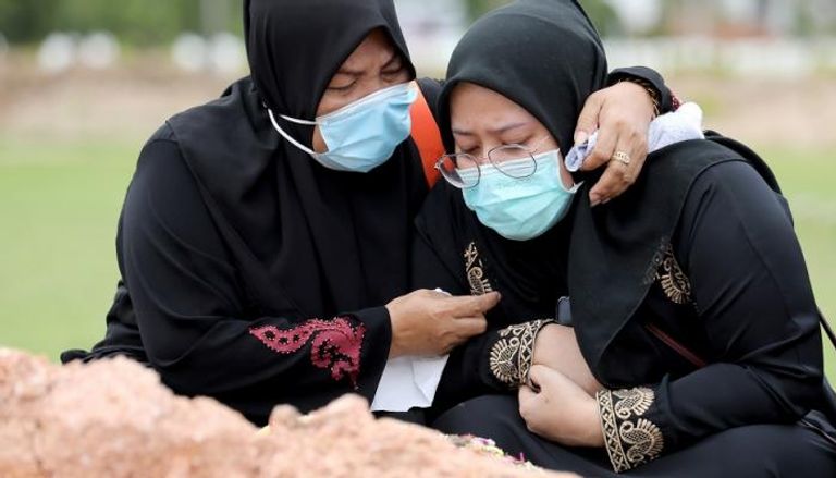 سيدتان تبكيان وفاة قريب لهما بفيروس كورونا في ماليزيا