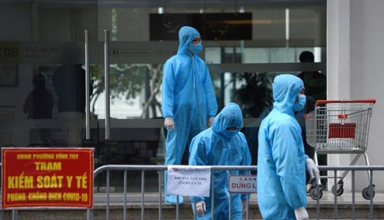 عاملون طبيون يرتدون بدلات واقية خارج مبنى خاضع للحجر الصحي في هانوي