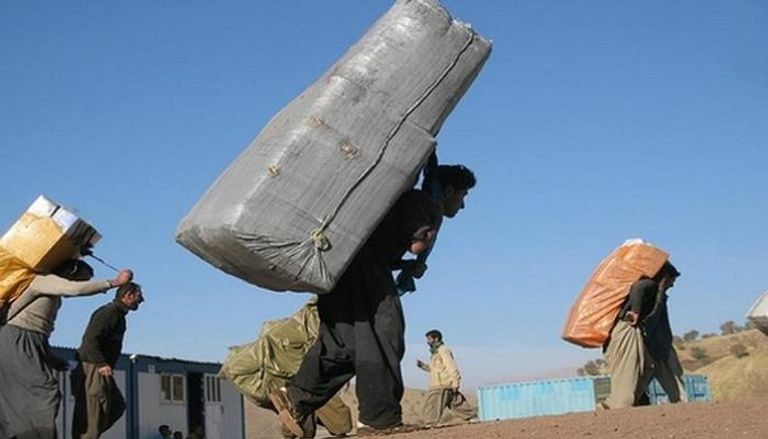 أكراد يعملون في نقل البضائع على ظهورهم عبر الحدود