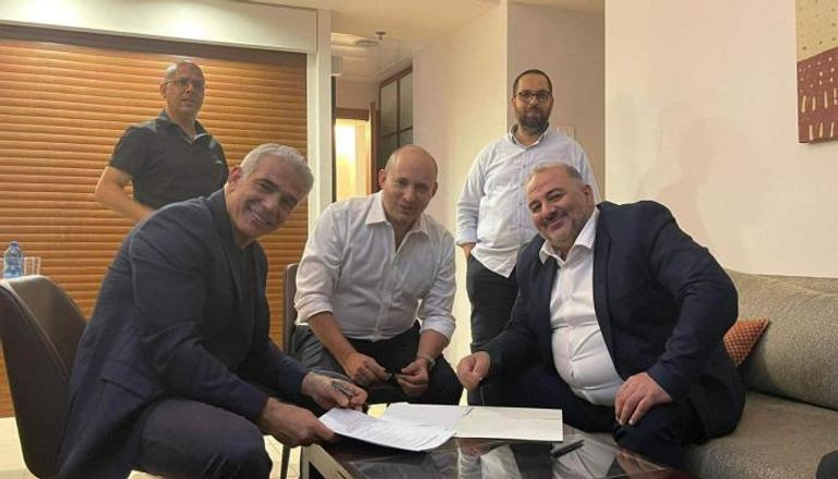 منصور عباس أثناء التوقيع على الاتفاق مع لابيد