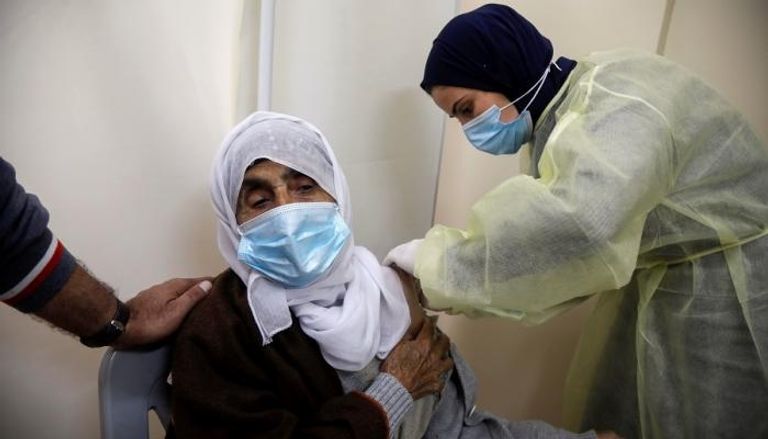 طبيبة فلسطينية تحقن سيدة بلقاح كورونا في الضفة الغربية المحتلة