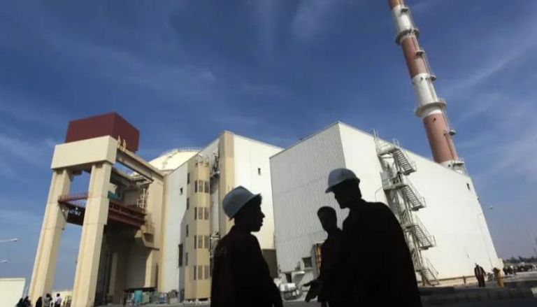 عمال إيرانيون أمام محطة بوشهر النووية