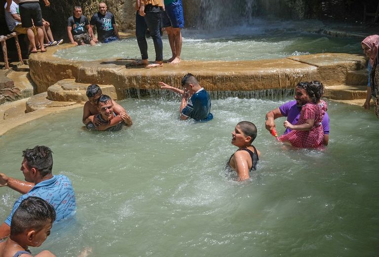 عراقيون يسبحون أسفل شلال هربا من شدة حرارة الطقس صيف لاهب في العراق في ظل انقطاع تام للكهرباء